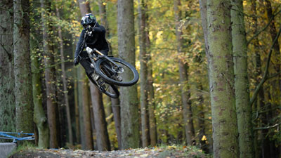 Fietser met integraalhelm springt op met een Cube Stereo ONE77 Fully mountainbike.