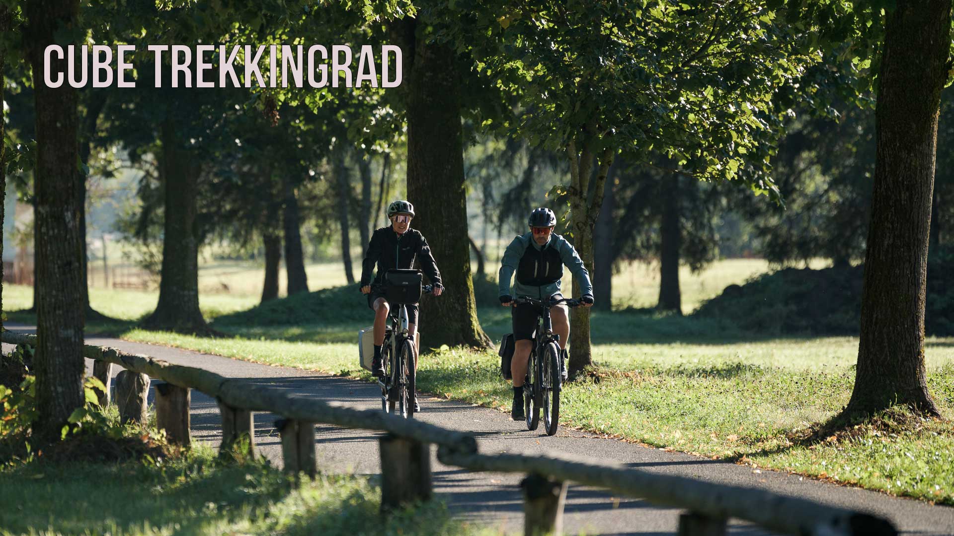 De foto heeft het label Cube trekkingfiets en laat een stel zien dat door een park rijdt op een fietspad.