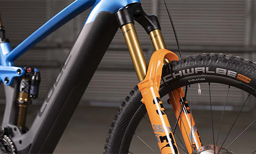 Je ziet een blauwe fiets met de nadruk op de vering van de vork.