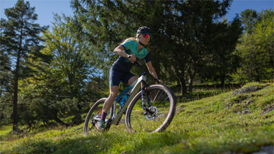 Je ziet een fietser op haar mountainbike. Ze fietst door steil terrein.