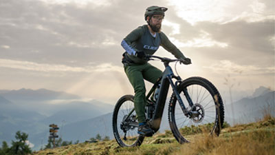Je ziet een man op een grijze Cube Stereo Hybrid e-bike, rijdend over een wandelpad.