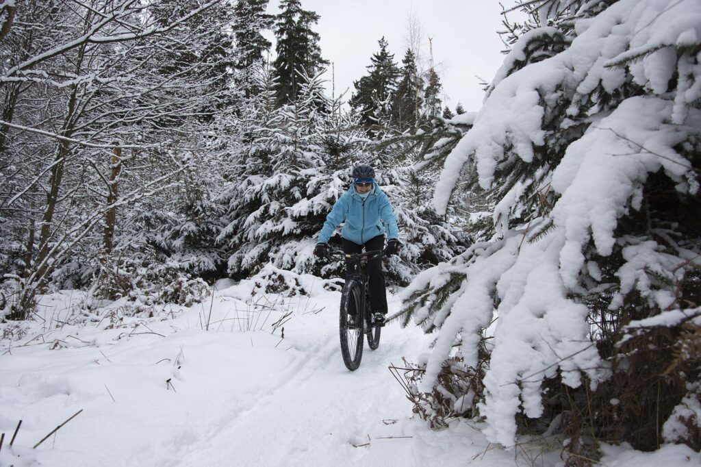 Vrouw fietst in de winter door de sneeuw &ndash; fietsen in koude weersomstandigheden