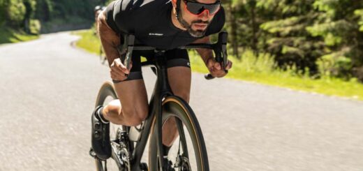 Man op een aero racefiets in diepe zithouding, met gestroomlijnde kleding en helm
