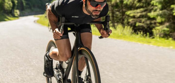 Man op een aero racefiets in diepe zithouding, met gestroomlijnde kleding en helm