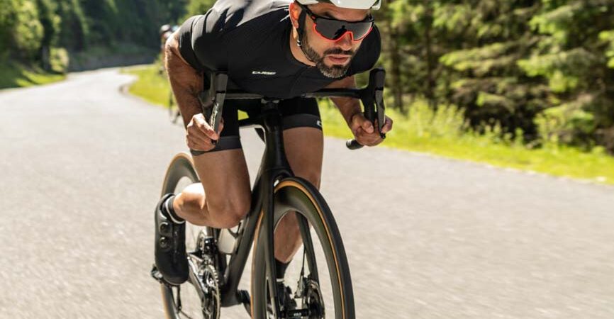 Man op een aero racefiets in diepe zithouding, met gestroomlijnde kleding en helm