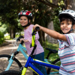 Twee kinderen op de fiets onderweg naar school – veilig naar school fietsen Twee kinderen op de fiets onderweg naar school – veilig naar school fietsen