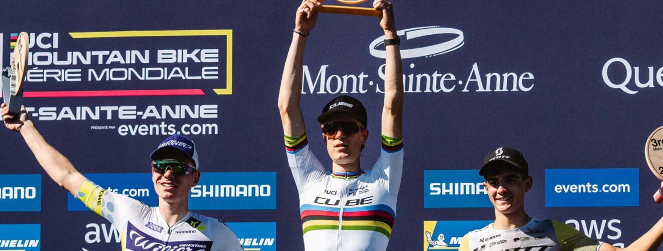 Finn Treudler viert de Cube Factory Racing-seizoensfinale 2025 in Mont-Sainte-Anne met de trofee in zijn handen, geflankeerd door de tweede en derde plaats op het podium.