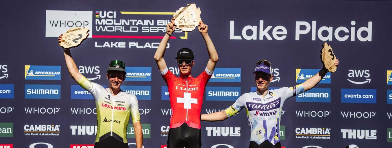 Finn Treudler juicht op het podium en heft trots de trofee omhoog voor zijn U23-overwinning in Lake Placid.