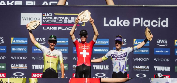 Finn Treudler juicht op het podium en heft trots de trofee omhoog voor zijn U23-overwinning in Lake Placid.